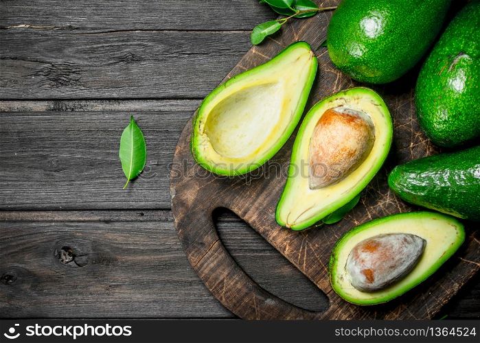 Avocado on a chopping Board. On a black wooden background.. Avocado on a chopping Board.