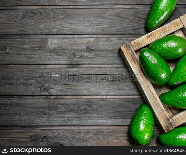 Avocado on a wooden dressing. On a black wooden background.. Avocado on a wooden dressing.