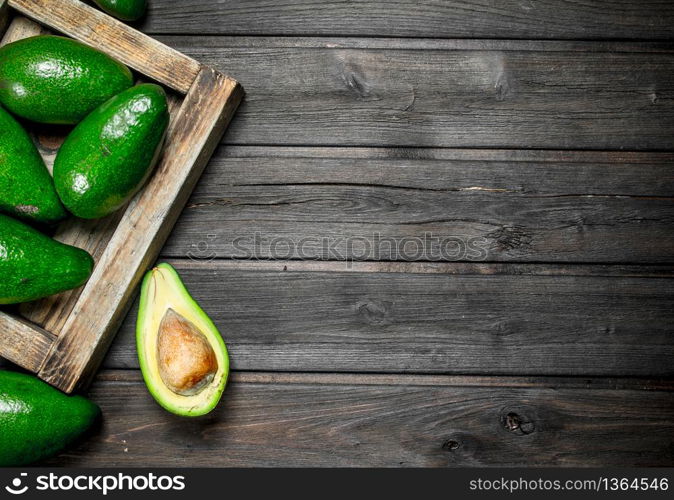 Avocado on a wooden dressing. On a black wooden background.. Avocado on a wooden dressing.