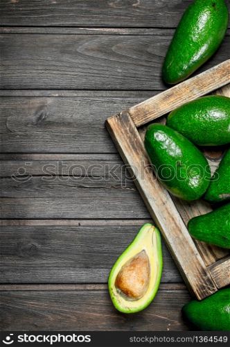 Avocado on a wooden dressing. On a black wooden background.. Avocado on a wooden dressing.