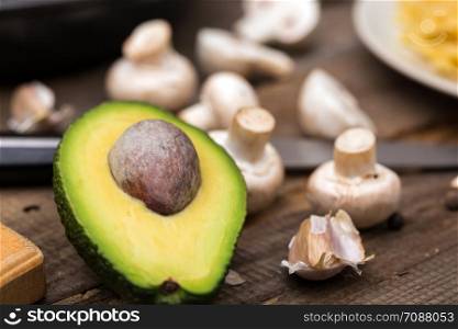 avocado on cutting board on wooden background and mushrooms