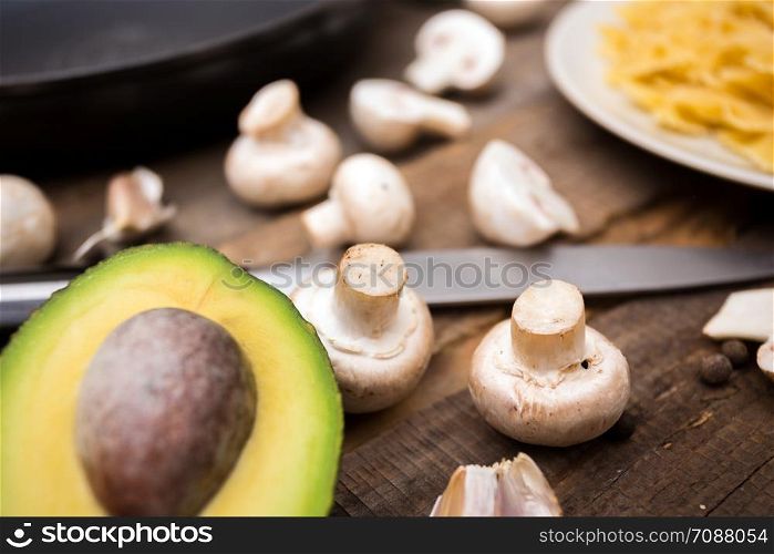 avocado on cutting board on wooden background and mushrooms