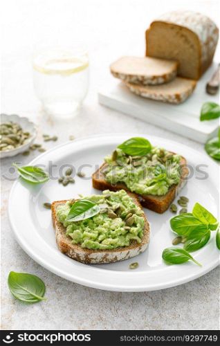 Avocado sandwich with pumpkin seeds. Healthy vegetarian avocado toast with rye bread for breakfast. Vegan menu
