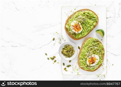 Avocado toast with boiled egg, seeds and sprouts on white background. Healthy diet food. Top view