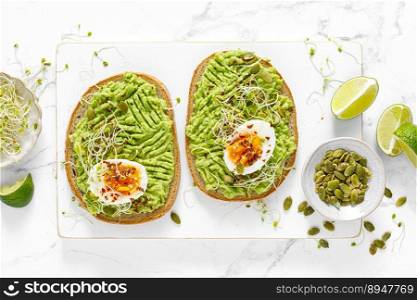 Avocado toast with boiled egg, seeds and sprouts on white background. Healthy diet food. Top view