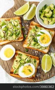 avocado toasts, healthy snack of grilled bread with guacamole slices avocado, boiled eggs, chia seeds and green onions. avocado toasts top view, healthy snack of grilled bread with guacamole slices avocado, boiled eggs, chia seeds and green onions