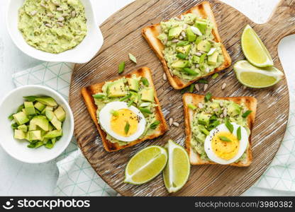 avocado toasts, healthy snack of grilled bread with guacamole slices avocado, boiled eggs, chia seeds and green onions. avocado toasts top view, healthy snack of grilled bread with guacamole slices avocado, boiled eggs, chia seeds and green onions