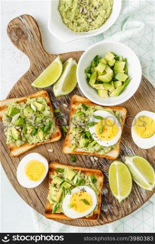 avocado toasts, healthy snack of grilled bread with guacamole slices avocado, boiled eggs, chia seeds and green onions. avocado toasts top view, healthy snack of grilled bread with guacamole slices avocado, boiled eggs, chia seeds and green onions