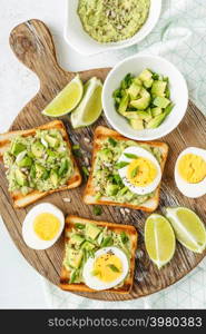 avocado toasts, healthy snack of grilled bread with guacamole slices avocado, boiled eggs, chia seeds and green onions. avocado toasts top view, healthy snack of grilled bread with guacamole slices avocado, boiled eggs, chia seeds and green onions