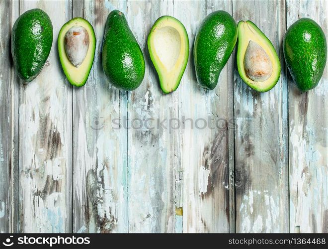 Avocado whole and cut with bone. On a white wooden background.. Avocado whole and cut with bone.