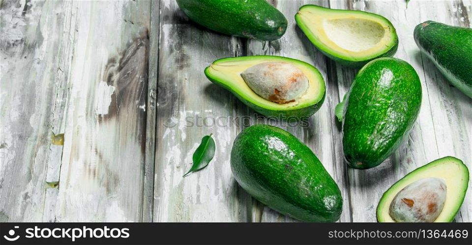 Avocado whole and cut with bone. On a white wooden background.. Avocado whole and cut with bone.