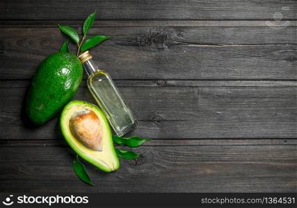 Avocado with leaves and a bottle. On a wooden background.. Avocado with leaves and a bottle.