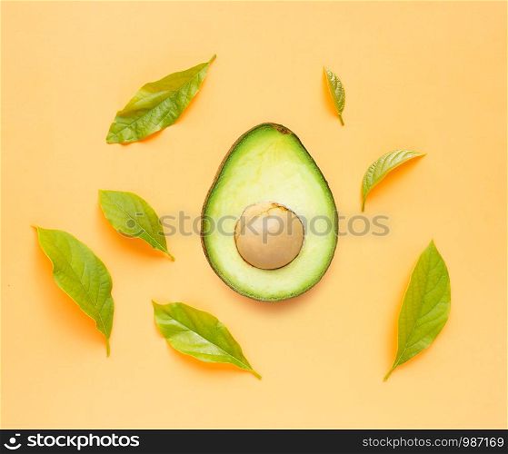 Avocado with leaves on orange background. Top view