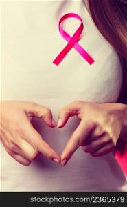Awareness of breast cancer. Close up of female hands make heart on pink ribbon symbol sign. Help and charity.. Breast cancer. Female hands make heart on pink ribbon