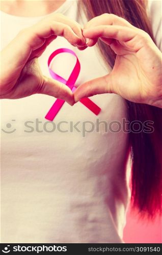 Awareness of breast cancer. Close up of female hands make heart on pink ribbon symbol sign. Help and charity.. Breast cancer. Female hands make heart on pink ribbon