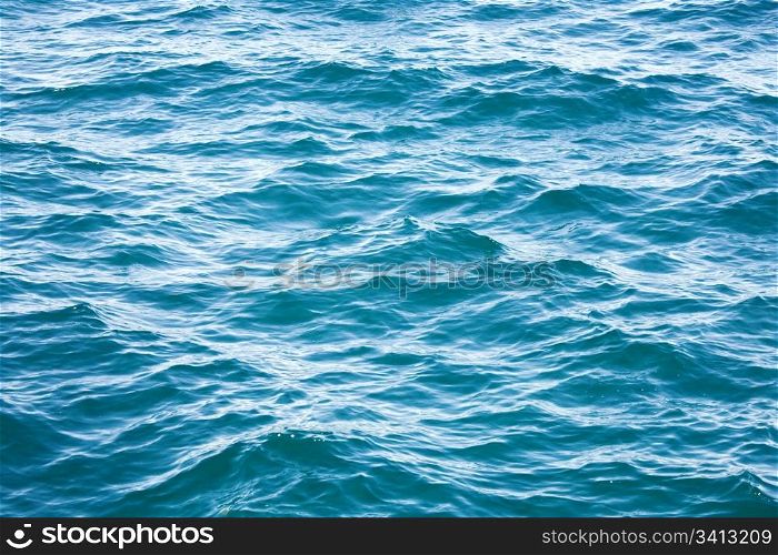 Azure sea water surface with ripple and cloud reflections