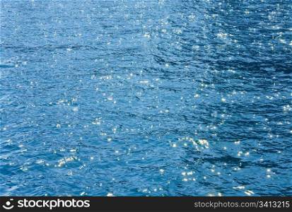 Azure sea water surface with ripple and sun reflections