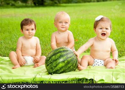 Babies with watermelon outdoors.
