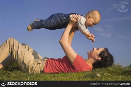 Baby and his mother are having outdoor fun together and they are smiling a lot. There are nice afternoon lights.