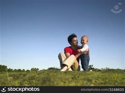 Baby and his mother are having outdoor fun together and they are smiling a lot. There are nice afternoon lights.