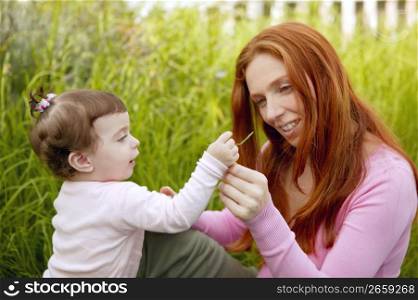 baby and redhead mother outdoor grass playing park together