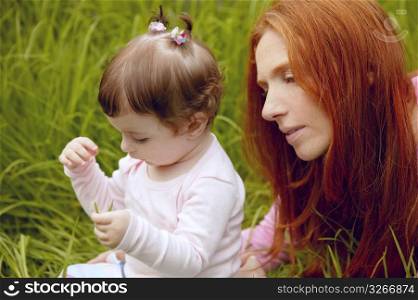 baby and redhead mother outdoor grass playing park together