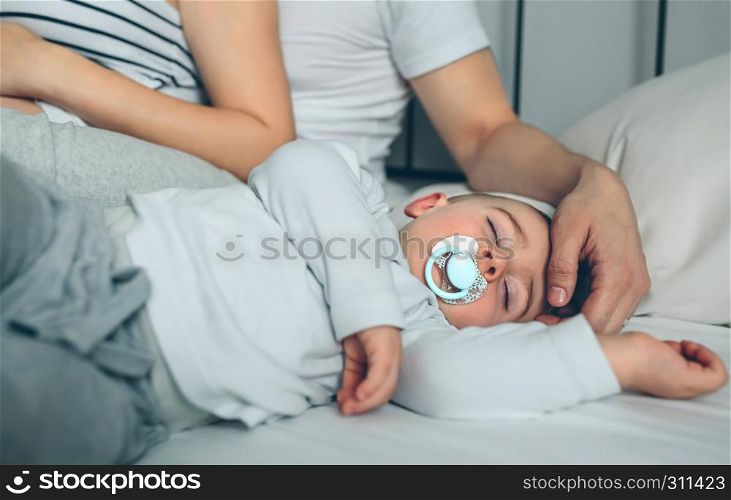 Baby asleep while his parents caress him. Baby asleep while parents caress