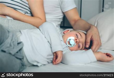 Baby asleep while his parents caress him. Baby asleep while parents caress