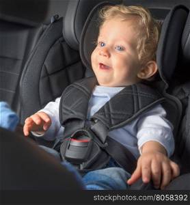 Baby boy 8 months old smiling in a safety car seat.