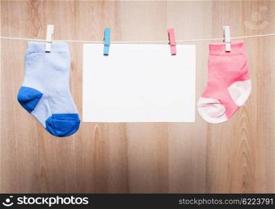 Baby boy and girl socks attached to the rope and blank card for greetings. Baby boy socks