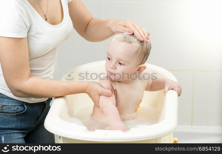 Baby boy having bath and looking at mother