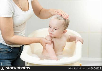 Baby boy having bath and looking at mother