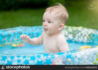 Baby boy having fun in swimming pool at garden
