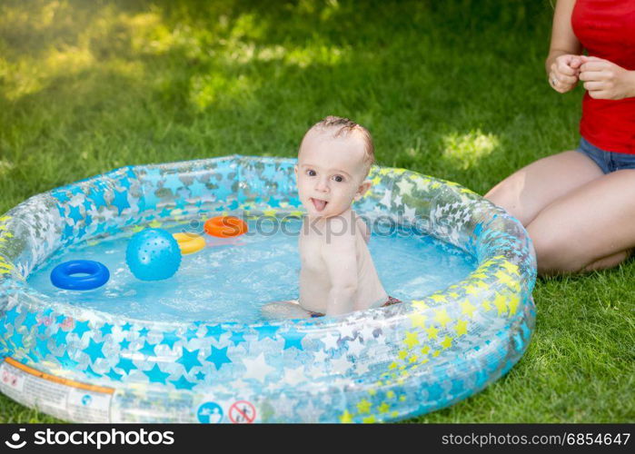 Baby boy in outdoor swimming pool playing with mother