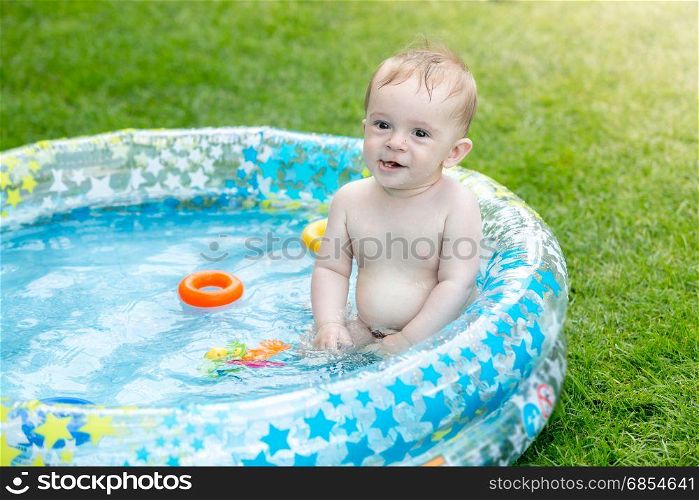 Baby boy in the inflatable swimming pool at backyard