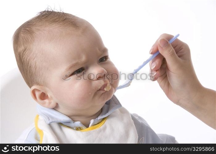 Baby Boy Is Fed With A Spoon And Has A Disapproving Expression