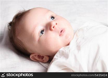 Baby boy lie on white diaper and look
