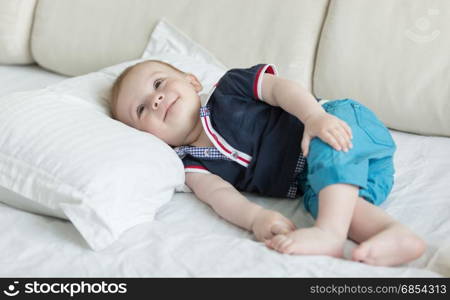 Baby boy lying on big pillow on bed