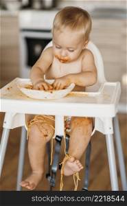 baby boy making mess with pasta