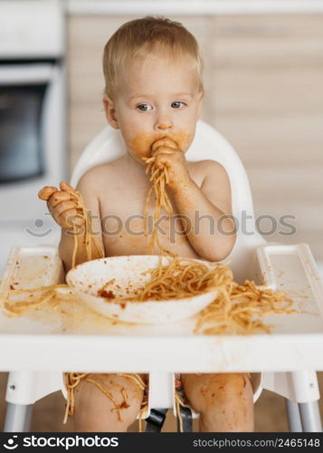 baby boy making mess with pasta alone