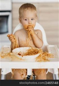 baby boy making mess with pasta alone