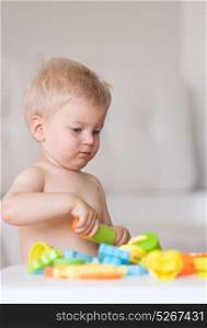 Baby boy playing and having fun with colorful modeling clay (plasticine or dough)