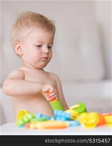 Baby boy playing and having fun with colorful modeling clay (plasticine or dough)