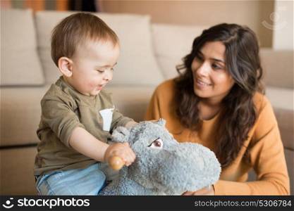 Baby boy playing with a rocking horse with mom&rsquo;s help