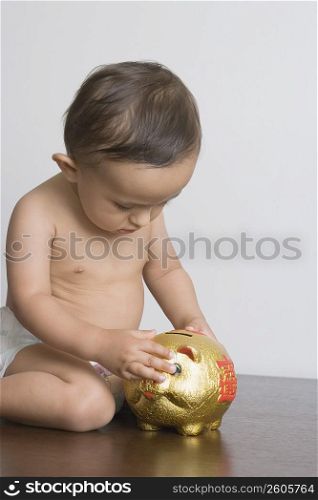 Baby boy playing with piggy bank