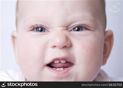 Baby boy pulls funny face with scrunched up nose