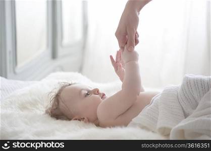 Baby boy reaches for mother&acute;s hand