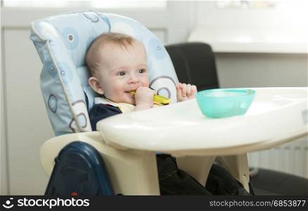 Baby boy siting in highchair on kitchen and eating