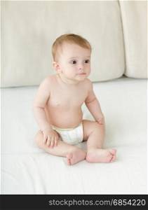 Baby boy sitting on bed at bedroom