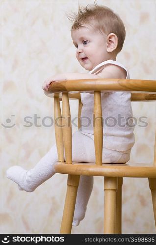 Baby boy sitting on high chair, laughing